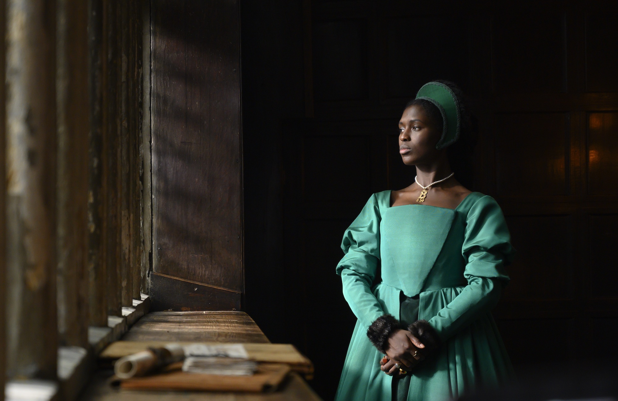 Woman staring out the window in a green Tudor style dress, in Anne Boleyn on Showmax