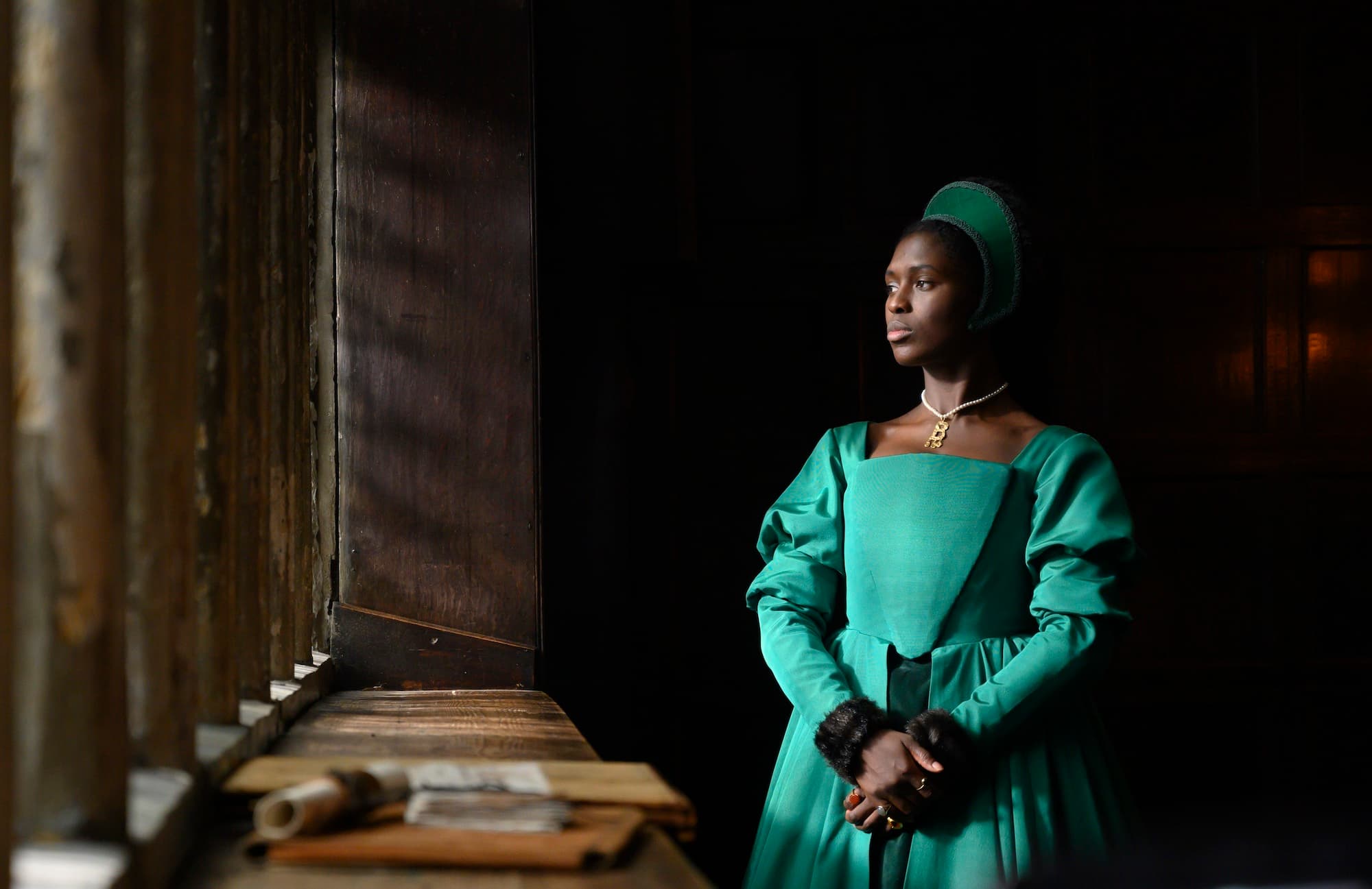 Woman staring out the window in a green Tudor style dress, in Anne Boleyn on Showmax