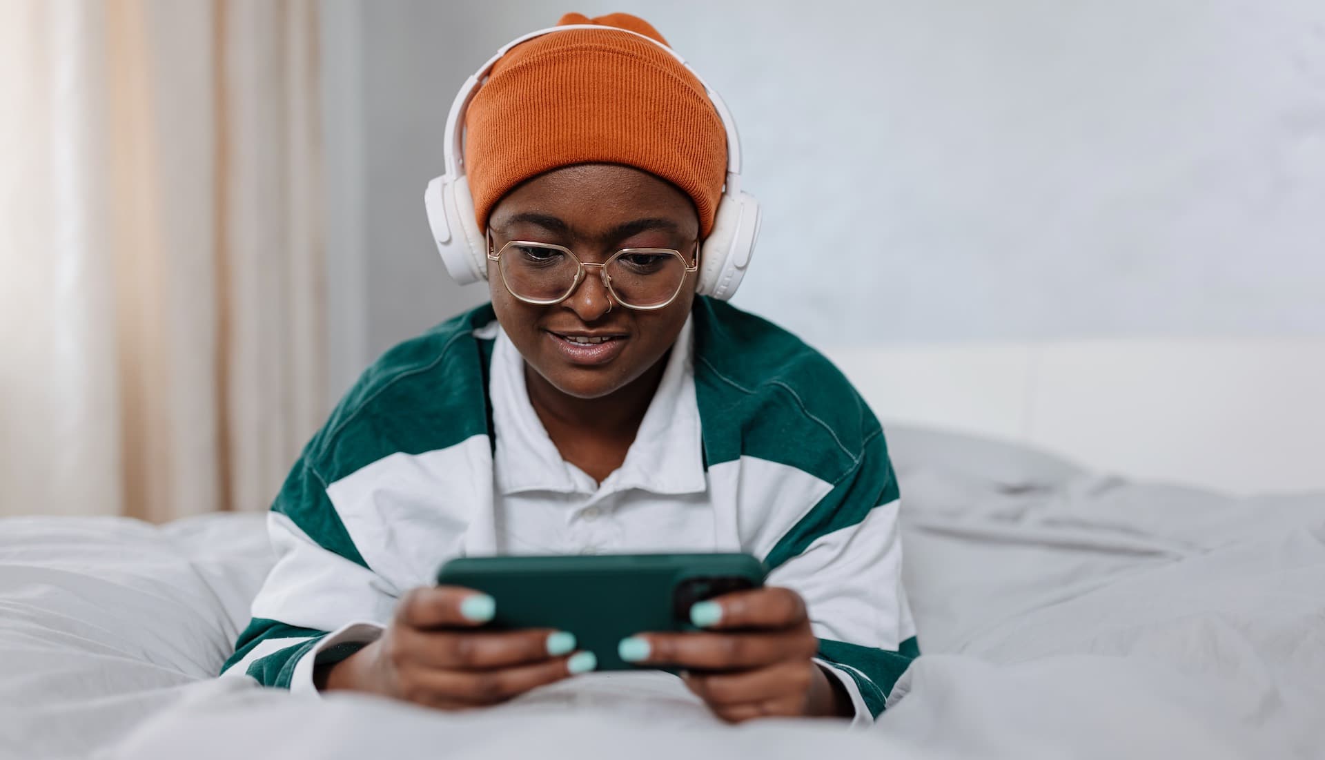 woman in beanie streaming on phone with headphones