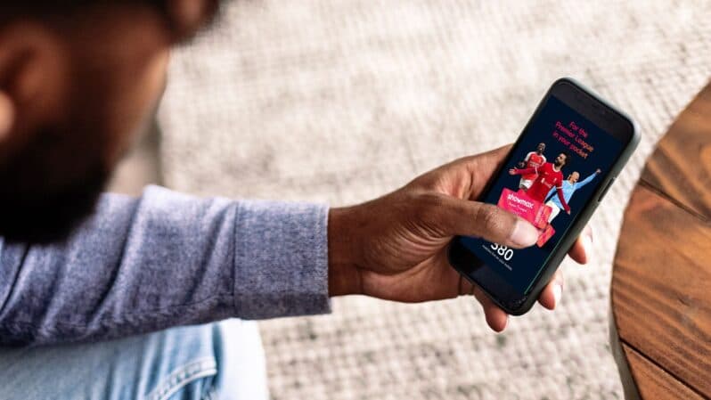 Man holding mobile device showing Showmax Premier League