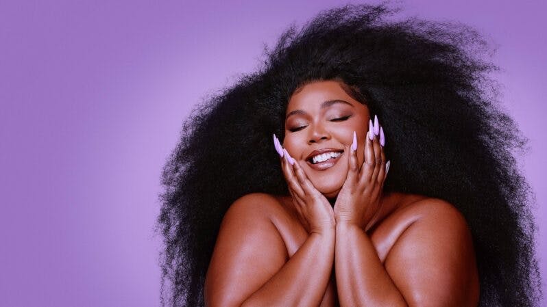 Lizzo with her face in her hands, smiling, in Love, Lizzo, on Showmax